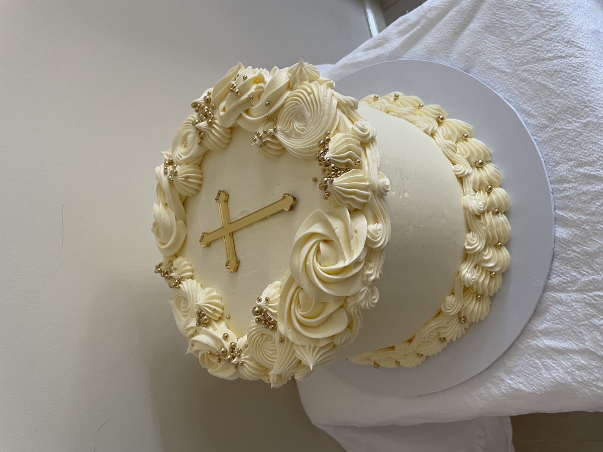 White christening cake with gold cross and rosettes