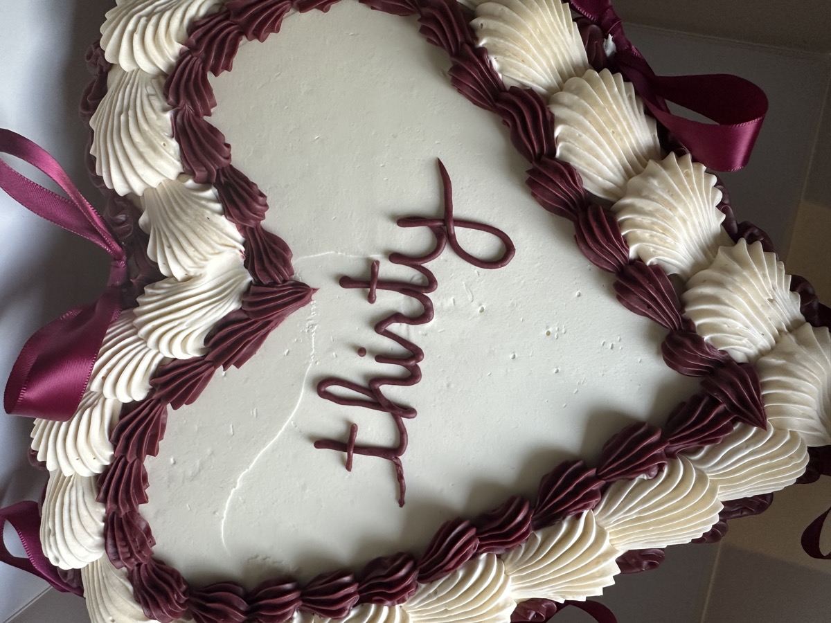 Heart-shaped birthday cake with burgundy and cream piping